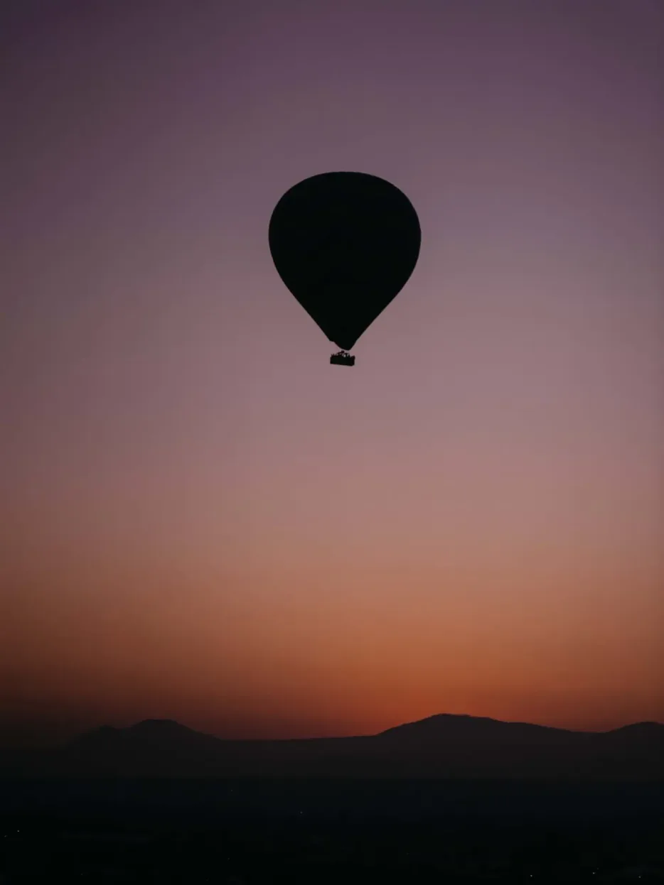 Globo aerostático a contraluz sobre el valle de Teotihuacán con el cielo lila del amanecer