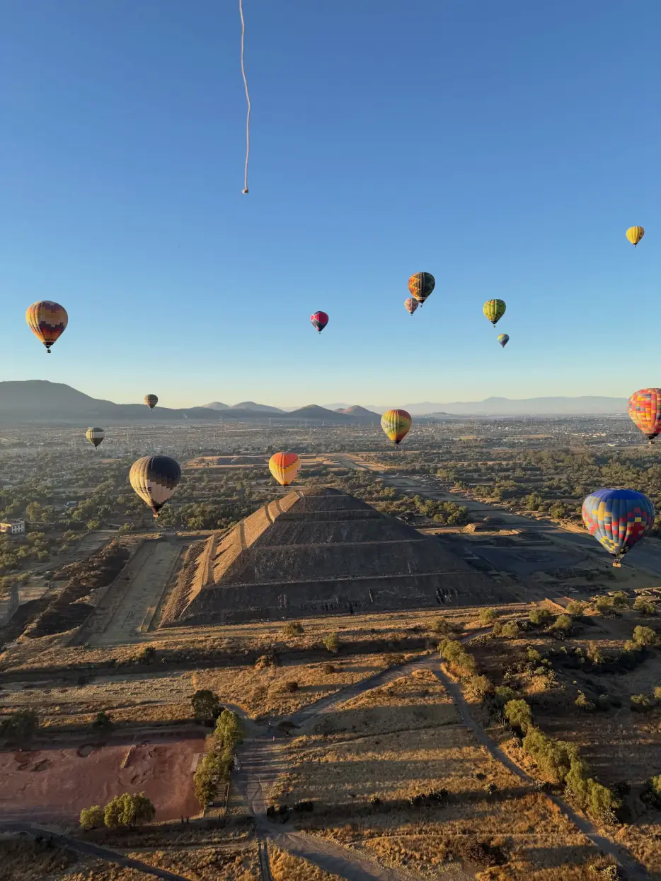 Pirámide del Sol y globos aerostáticos bañados por la luz dorada del amanecer en Teotihuacán